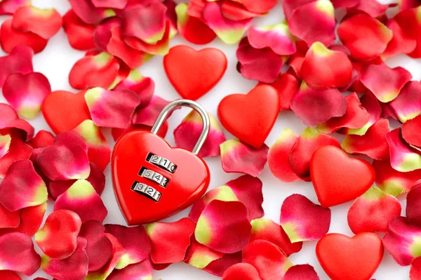 Padlock heart-shape on a background of red petals — Stock Photo, Image