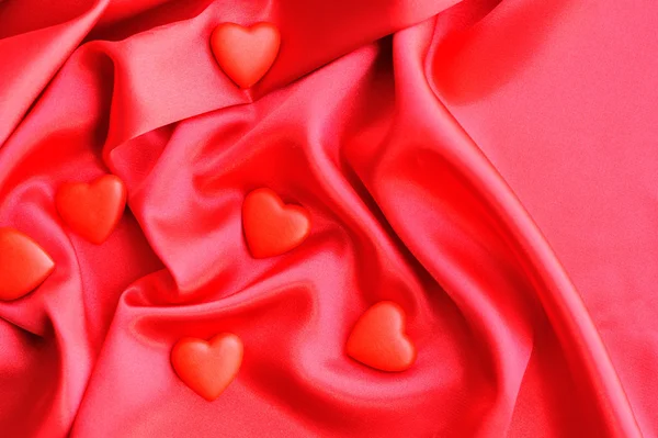 Saten kumaş arka plan üzerinde kırmızı Kalpler — Stok fotoğraf