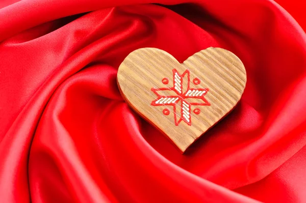 Corazón de madera sobre fondo satinado rojo — Foto de Stock