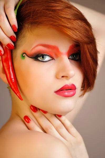 Retrato de mujer hermosa con maquillaje rojo creativo mantiene chiles —  Fotos de Stock