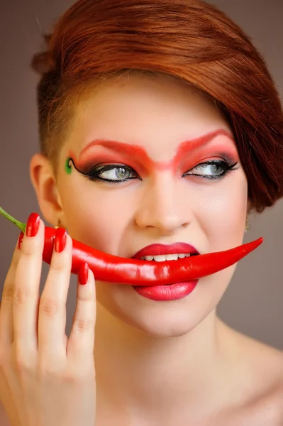Portret van mooie vrouw met creatieve rode make-up houdt chilipepertjes — Stockfoto