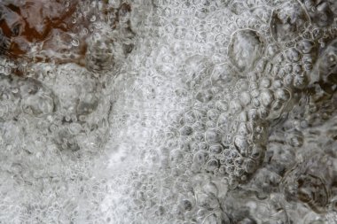 Arkaplanda turkuaz nehir yüzeyi olan temiz su damlaları havada yakalanır.