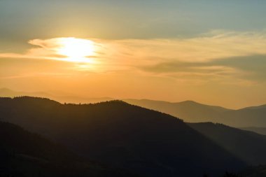 Güneşli ışıklarla dağlarda görkemli günbatımı
