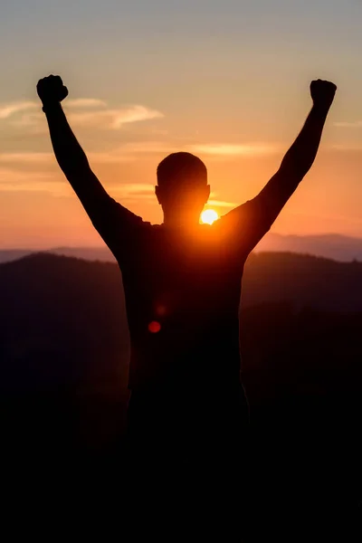 Free man raising arms to golden sunset summer sky. Freedom, success and hope concept. Boy relaxing and enjoying peace and serenity on beautiful nature