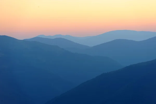 Salida del sol sobre siluetas de montañas — Foto de Stock