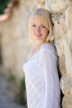 Taştan bir duvar tarafından duran güzel sarışın kadın