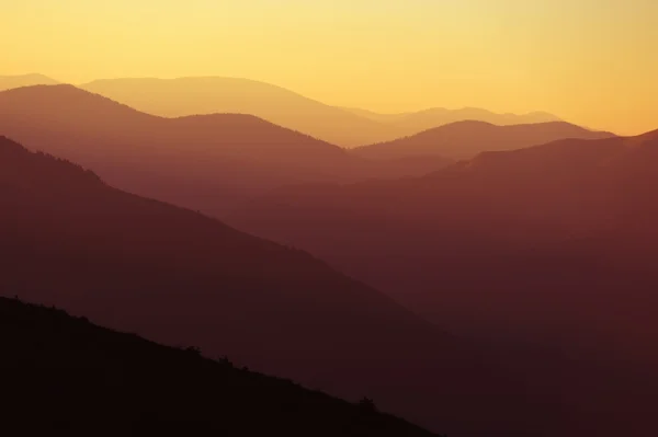 Salida del sol sobre siluetas de montañas — Foto de Stock