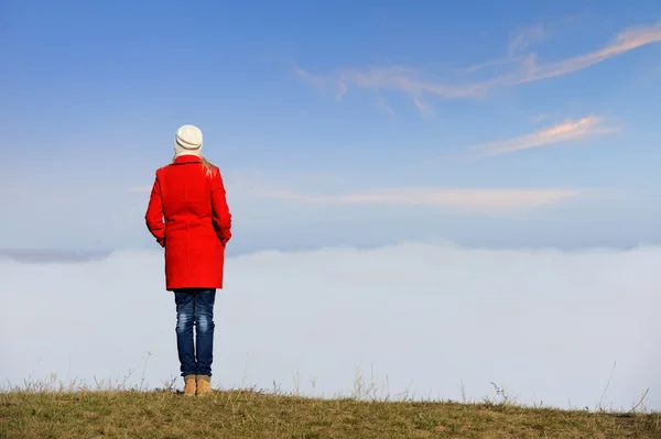 Frau steht auf einem Hügel über den Wolken — Stockfoto