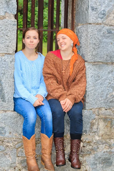 Две девушки, сидящие в каменном окне — стоковое фото