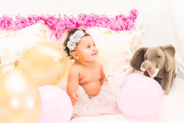 Yastıklar ve balon ile oturan bebek kız