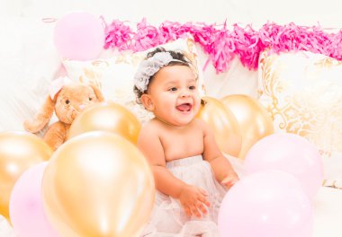 Yastıklar ve balon ile oturan bebek kız