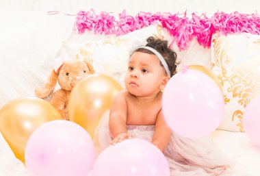 Yastıklar ve balon ile oturan bebek kız