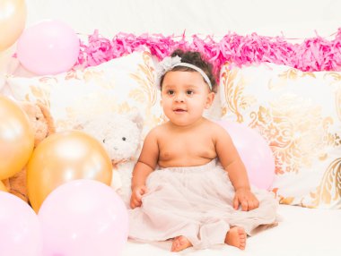 Yastıklar ve balon ile oturan bebek kız