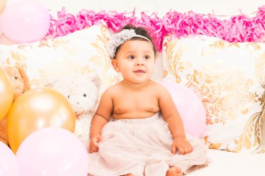 Yastıklar ve balon ile oturan bebek kız