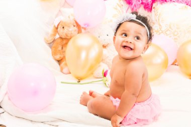 Yastıklar ve balon ile oturan bebek kız