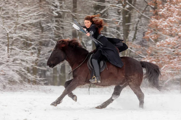 a woman rides swiftly past on horseback and shoots a bow