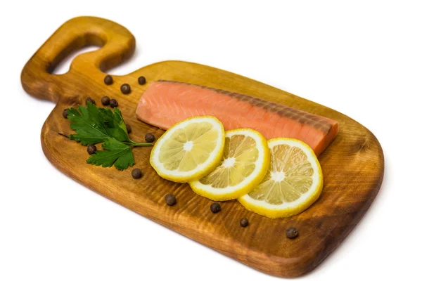 Filetto di salmone crudo con limone, pepe nero e prezzemolo su una tavola isolata su bianco — Foto Stock