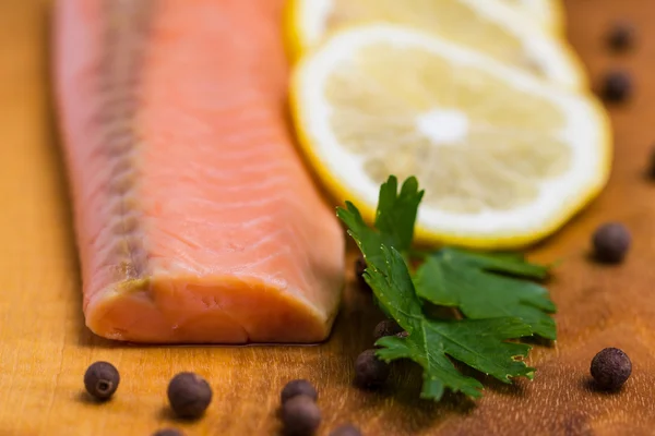 Raw salmon fillet with lemon, black pepper and parsley on a board — Stock Photo, Image