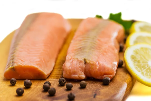 Raw salmon fillet with lemon, black pepper and parsley on a board isolated on white — Stock Photo, Image