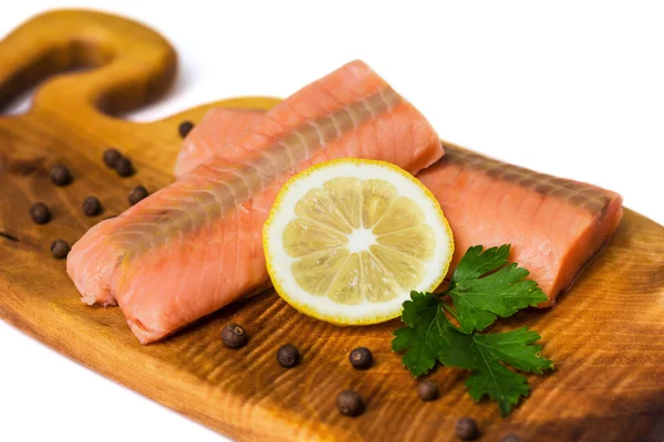 Raw salmon fillet with lemon, black pepper and parsley on a board isolated on white — Stock Photo, Image