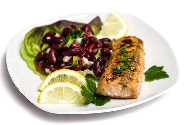 Filetto di salmone grigliato con insalata di fagioli, limone e prezzemolo isolato su bianco — Foto Stock