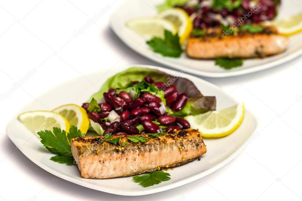 Salmon fillet grilled with bean salad, lemon and parsley isolated on white