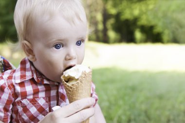 açık havada bahar Parkı'yeşil çimenlerin üzerinde dondurma yeme gülümseyerek mutlu bir çocuk