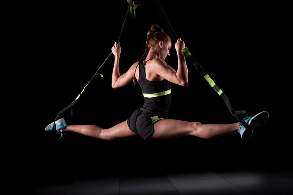 Jovem mulher atraente faz divide crossfit alongamento com tiras de fitness trx no estúdio de ginásios — Fotografia de Stock