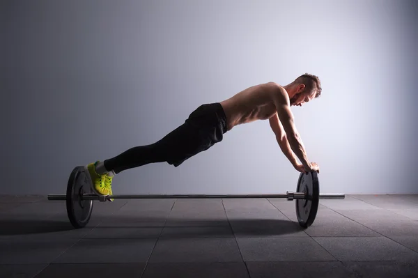 Um homem exercitando posição prancha fitness sobre os exercícios barbel em silhueta estúdio tecla escura — Fotografia de Stock