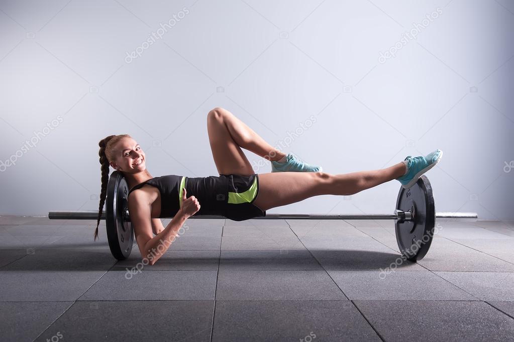 one smiling young woman with batbel showing thumbs up in gym