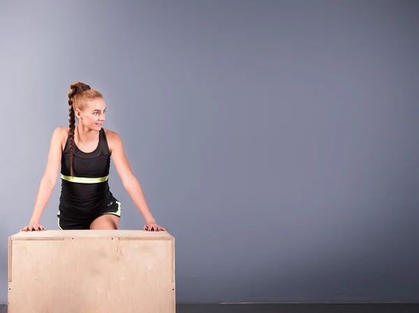 Beautiful sports woman doing push ups on fit box at gym