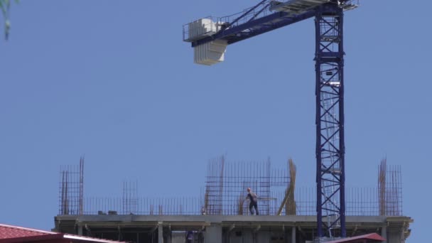 Profesjonalni budowniczowie w kombinezonach stawiają metalową ramę do budowy budynku wielokondygnacyjnego. — Wideo stockowe