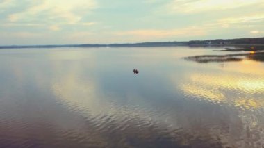 Altın gün doğumu. Balıkçı silueti ve teknesi, balıkçı yaşam tarzı. Sudaki bir teknedeki balıkçının hava görüntüsü.
