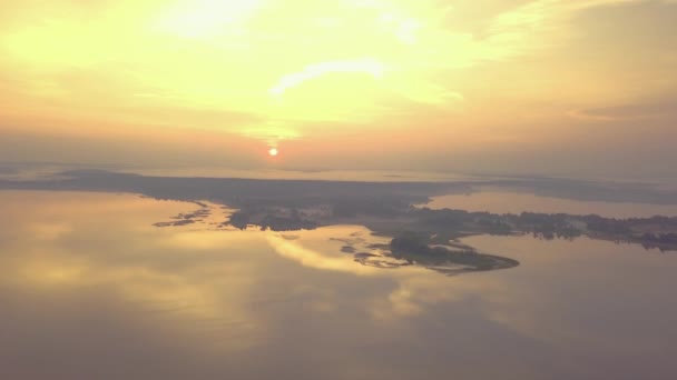 Beautiful golden sunrise over the serene surface of the water. Pink and gold clouds are reflected in the water, golden hour. Dawn, nature, drone shooting — Stock Video