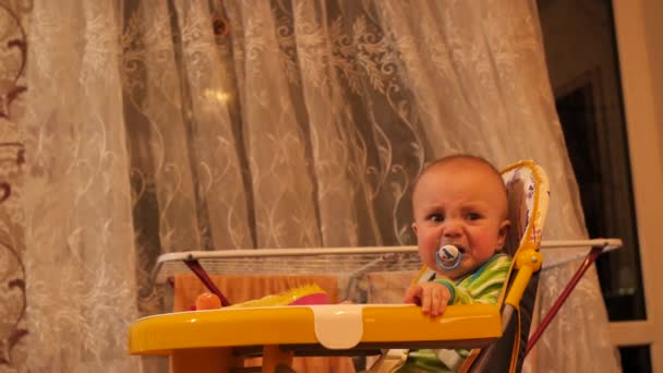 Little baby boy with soother in mouth who sitting in chair and crying 4K slow mo — Stock Video