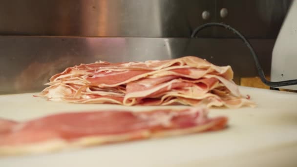 Someone packs sliced prosciutto, jamon, Parma ham into packaging for further sale. National Spanish dish, Italian dish. Meat, pork, farm product — Stock Video