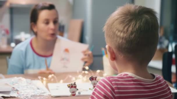 Las mamás y el hijo se están preparando para el nuevo año y la Navidad aprender a dibujar Santa Claus — Vídeos de Stock