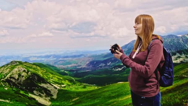 一位美丽的女子在山上远足，探索大自然，用相机拍照，拍摄周围的自然景观 — 图库视频影像