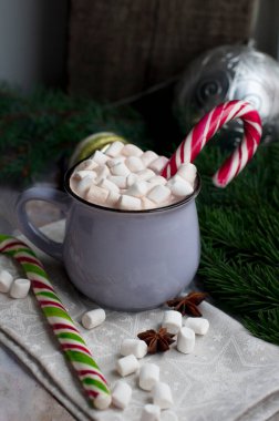 Bir fincan sıcak kakao, marşmelov ve Noel Baba personeli. Yılbaşı ve noel kakaosu, köknar dalıyla marşmelov ve gri arka planda tatlılar..