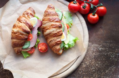 Jambonlu, peynirli, taze salatalı, domatesli, yumurtalı ve salatalıklı kruvasan sandviçi. Taze kruvasan sandviçli kahvaltı. Üst görünüm