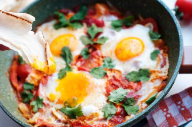 Geleneksel İsrail mutfağı Shakshuka yemeği. Domatesli yumurta, biber, soğan, kişniş ve pide. 