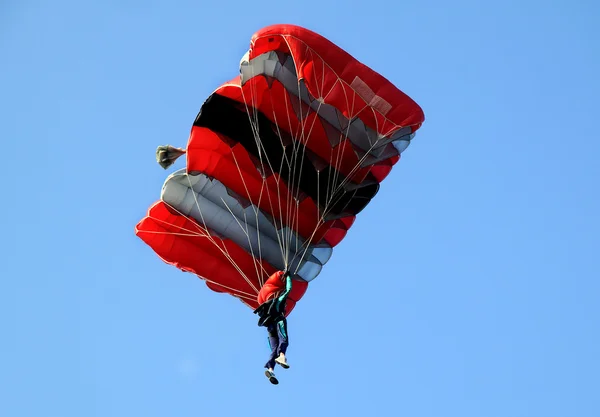 Red and black sail parachute on blue sky