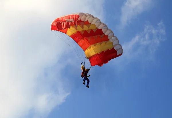 Parachute de voile jaune et rouge sur ciel bleu Image En Vente