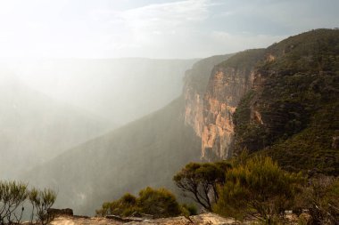 Şiddetli rüzgar ve yağmur, güneş içeri girip çıkarken yağar. Grose Vadisi ve dağ yamaçlarının manzarası.
