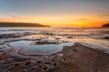 Sydney Avustralya 'ya yakın Malabar sahilinden gün doğumu. Sağda, yerlilerin sabah yüzeceği bir okyanus taşı havuzu var..