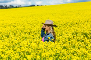 Çiftçinin dişisi, altın kanola ekinlerinin tampon tarlalarına bakıyor.