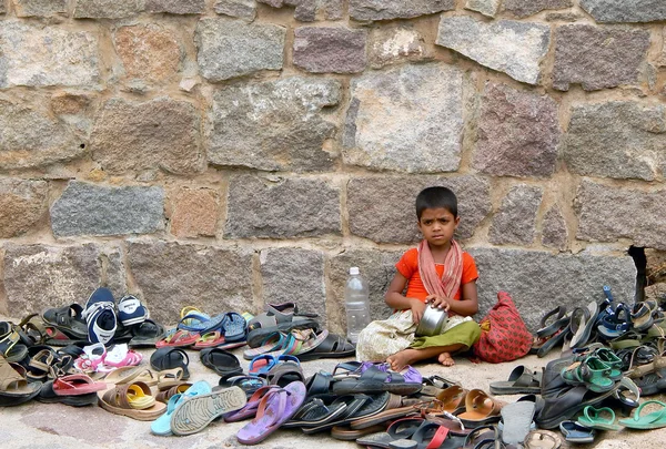 Indian girl keep watch on foot wear left outside Hindu temple — Stock Photo, Image