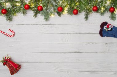 Çam ağacından dallarla bembeyaz arkaplanda kırmızı süsler, şeker kamışı, oyuncak ve hediye dolu bir Noel ortamı yaratıyor.