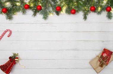 Çam dalları, kırmızı süslemeler, şeker kamışı ve beyaz ahşap arka planda hediyeler ile Noel atmosferi yaratarak fotokopi alanı oluşturan bir Noel dairesi.