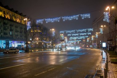 Kyiv, Ukrayna. Gece geniş şehir caddesi tatil aydınlatma kemerleri ve ışıldayan trafik ile süslenmiş neşeli kış kentsel atmosferi yaratıyor.